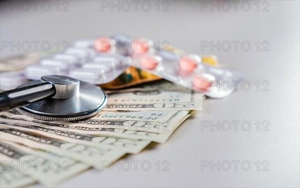 Stethoscope with medicaments on dollar bills. High cost of medical health with stethoscope. Close up of stethoscope with pills on dollar bills