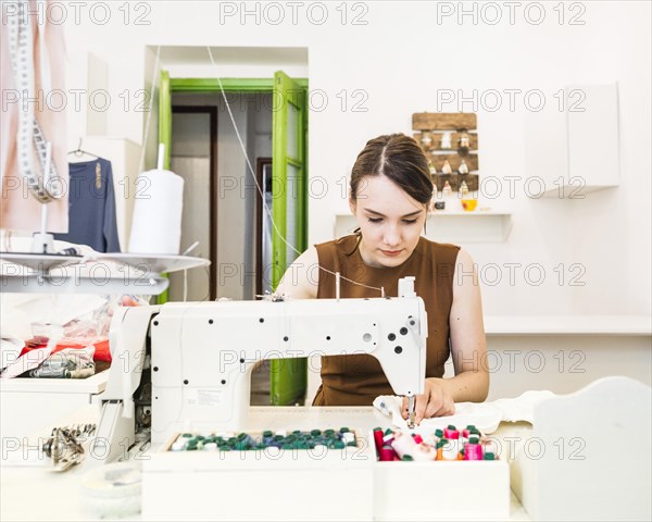 Beautiful female designer sewing fabric sewing machine