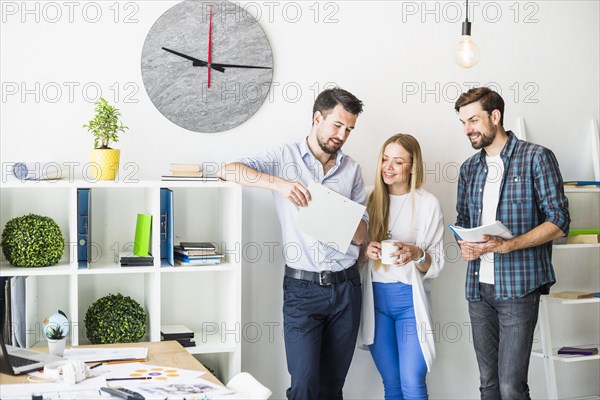 Group smiling young businesspeople looking document office
