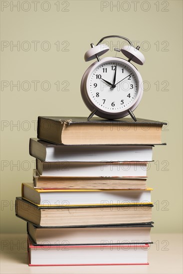 Alarm clock top stacked books wooden desk