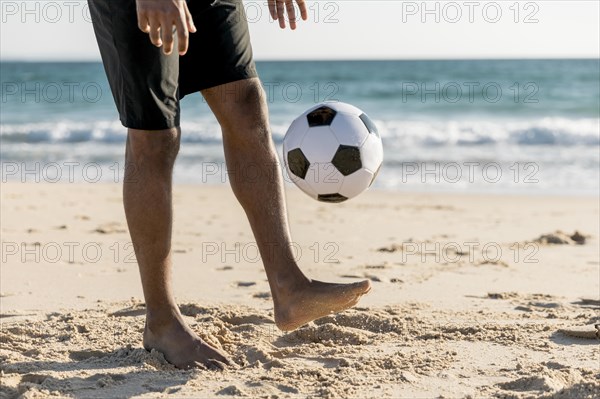 Male tossing ball up playing game beach