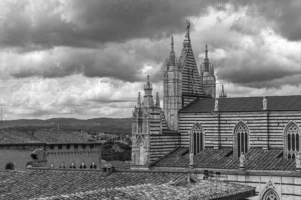 Dark clouds over the cathedral of Siena with its black and white striped marble facade