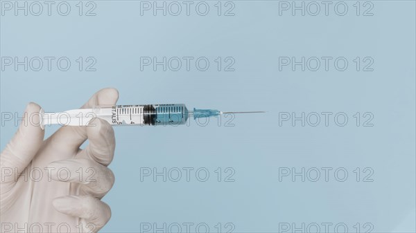 Hand with glove holding syringe