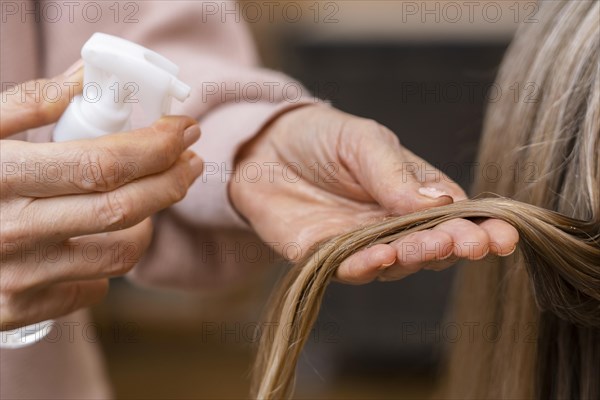 Hairdresser holding tuft hair spraying with water