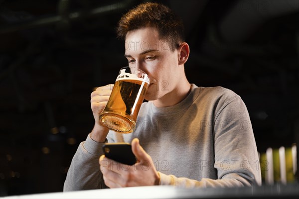 Medium shot man with phone beer mug