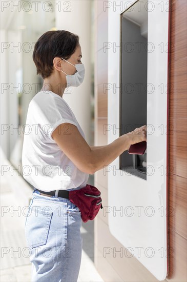 Side view woman bank atm with mask