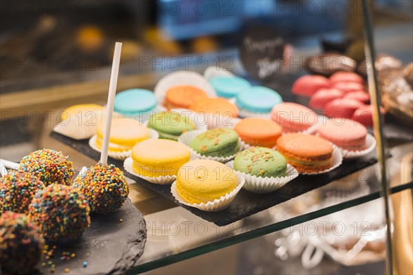 Chocolate cake pops with colorful sprinkles macaroons display cabinet