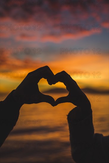 Couple making heart from hands sea shore