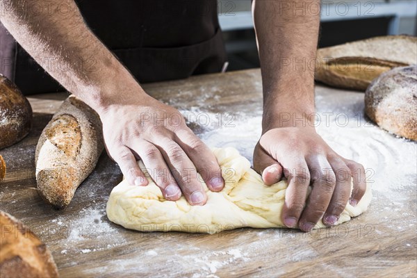 Close up male baker s hand kneading dough table