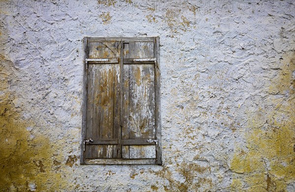 Weathered house facade with an old closed window