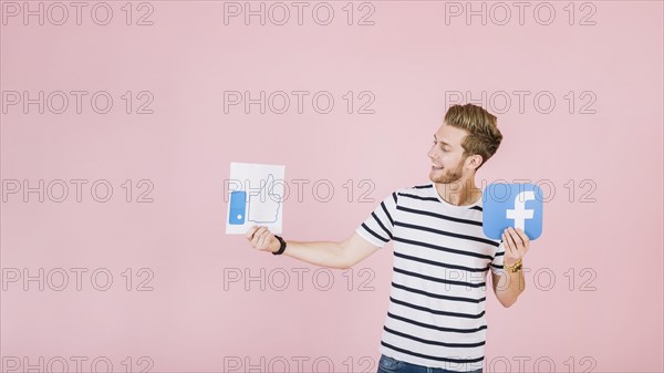 Smiling young man holding like facebook icon