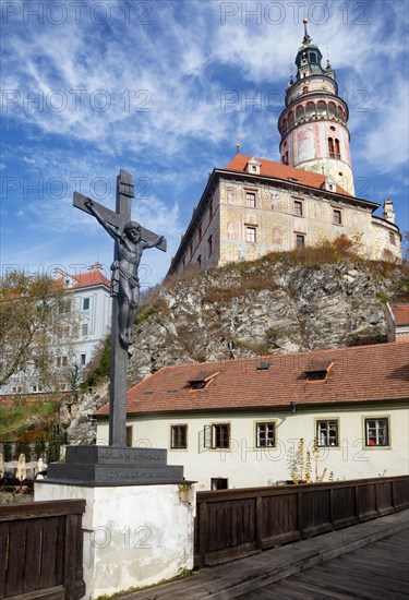 Pedestrian bridge over the Vltava with wayside cross and Krumlov Castle with castle tower