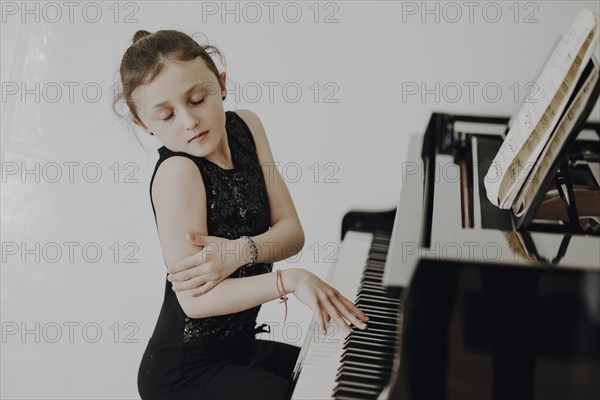 Elegant girl sits at a concert grand piano and plays the piano