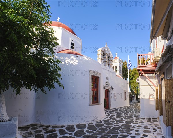 Beautiful close view of traditional Greek Orthodox church in typical Greek island town. Red dome