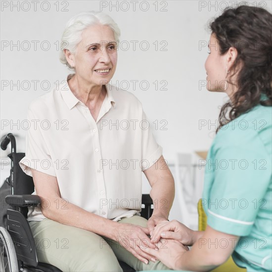Happy disabled nurse sitting wheel chair looking caretaker