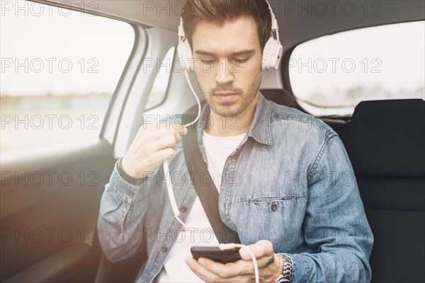 Young man listening music headphone while travelling car