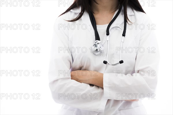 Portrait female doctor holding stethoscope around her neck with arm crossed against white backdrop