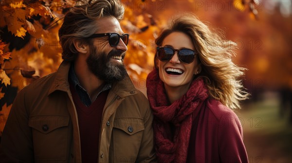 Warmly dressed young loving couple laugh as they enjoy the beautiful fall leaves in the park