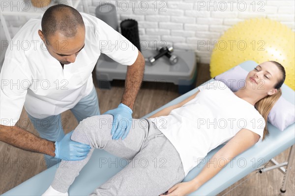 Male physiotherapist checking woman s knee