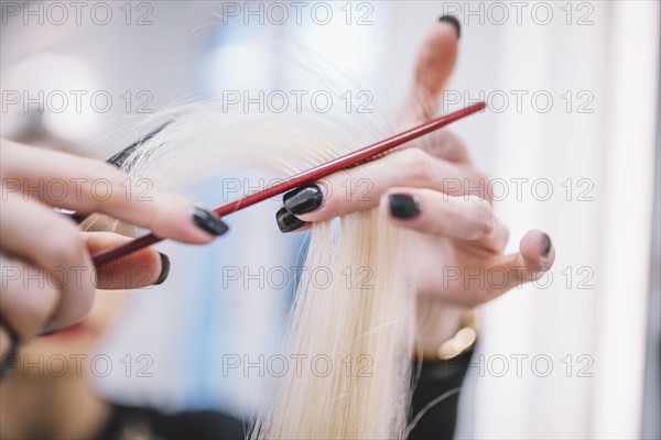 Close up stylist cutting fair hair