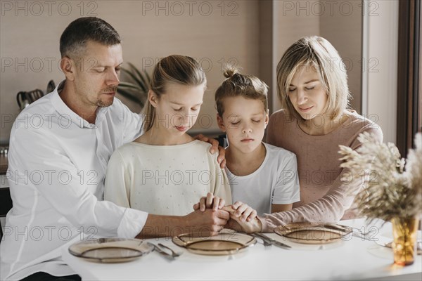 Family praying while holding their hands together