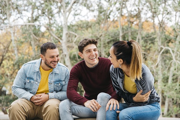 Multiethnic friends telling funny stories sitting park