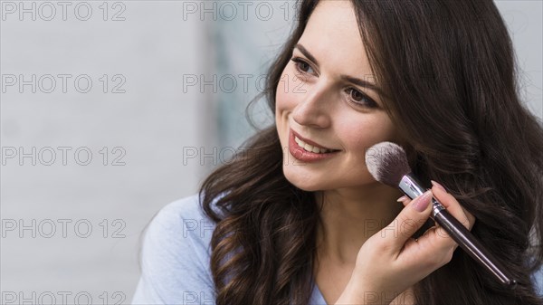 Smiling woman powdering cheek