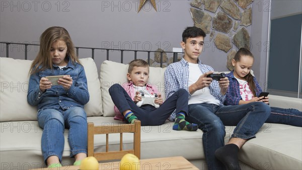 Boys playing video games girls using smartphones