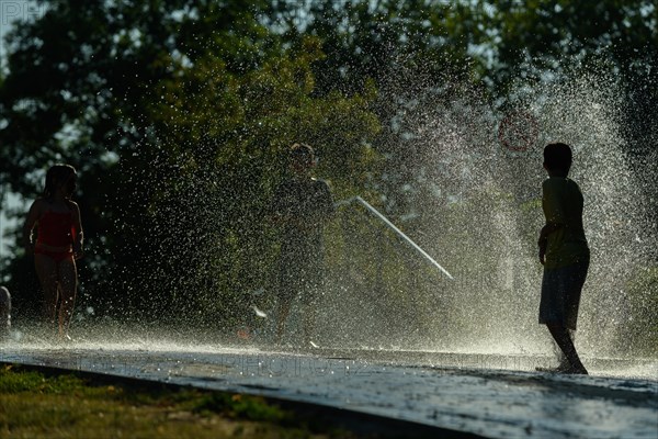 Children playing water in scorching weather in a park. Kehl