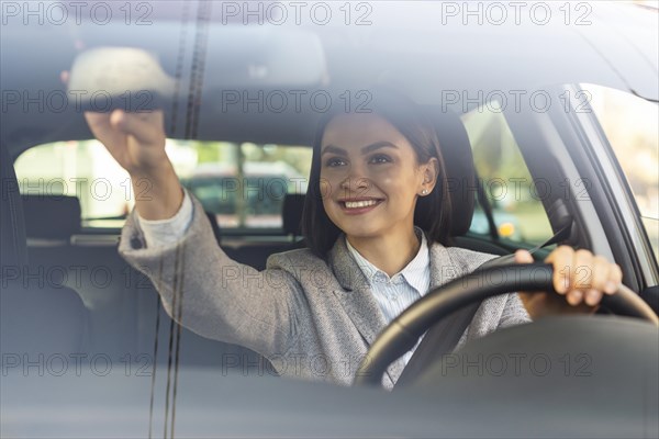 Smiley businesswoman adjusting her car s rear view mirror