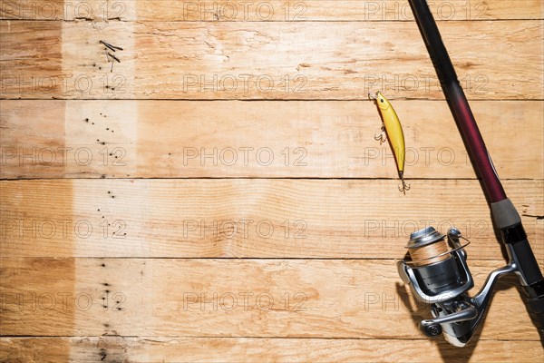 Fishing rod with yellow fishing bait wooden plank