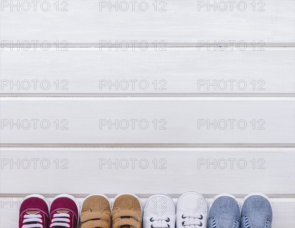 Baby concept with four pairs shoes space wooden surface