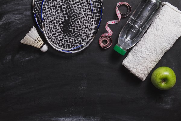 Composition with badminton racket water bottle apple