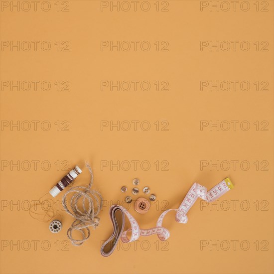 Brown spool string buttons measuring tape orange backdrop