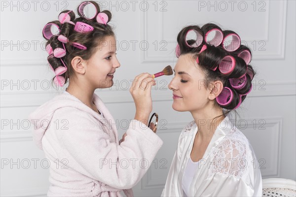Daughter putting powder mothers forehead