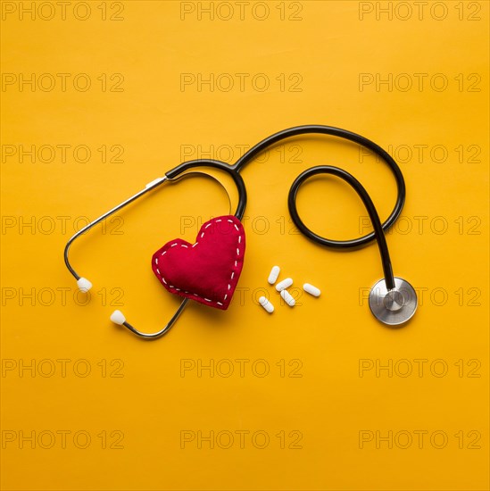 High angle view stethoscope stitched heart medicines yellow backdrop