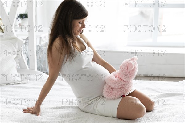 Pregnant woman playing with teddy bear