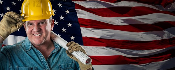 Male contractor wearing blank yellow hardhat over waving american flag background banner