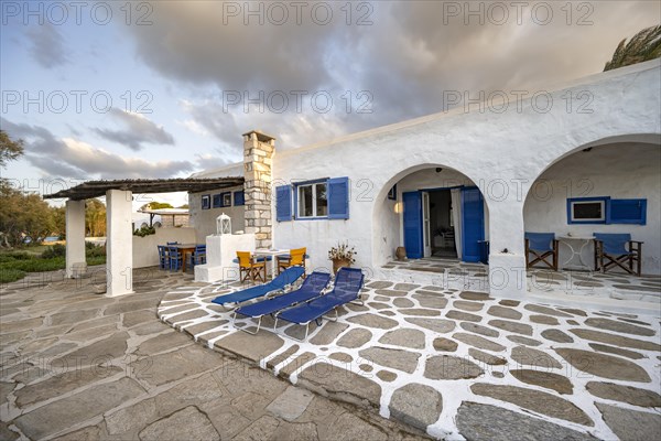 White Cycladic house with terrace with chairs and sun loungers