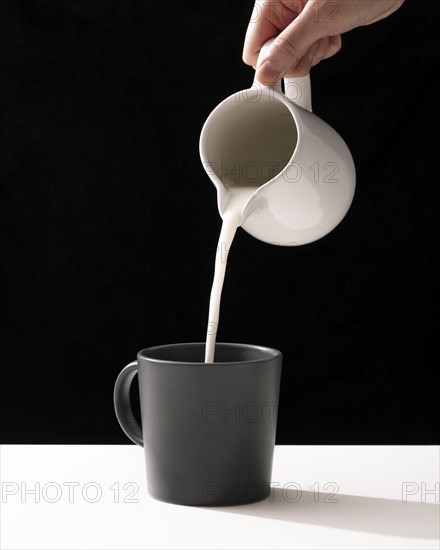 Front view hand pouring milk into mug