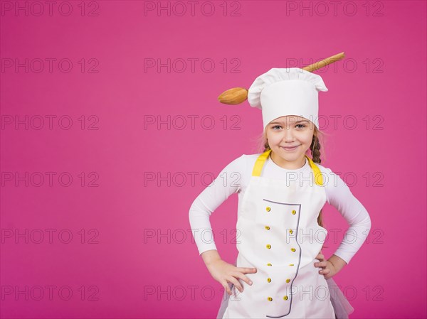 Cute girl cook standing with ladle chefs hat