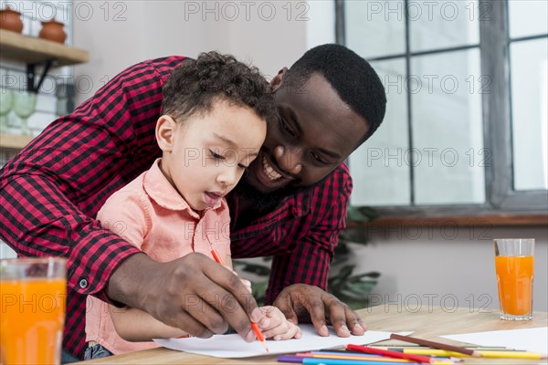 Happy black father son drawing table