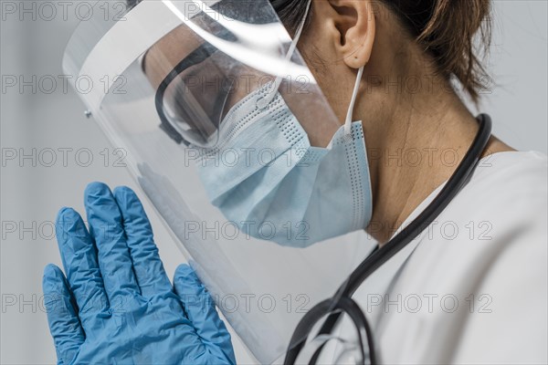 Side view female doctor with face shield medical mask praying