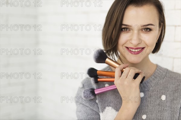 Smiling woman with makeup brushes