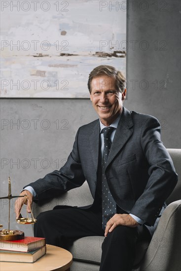 Confident male mature lawyer sitting office