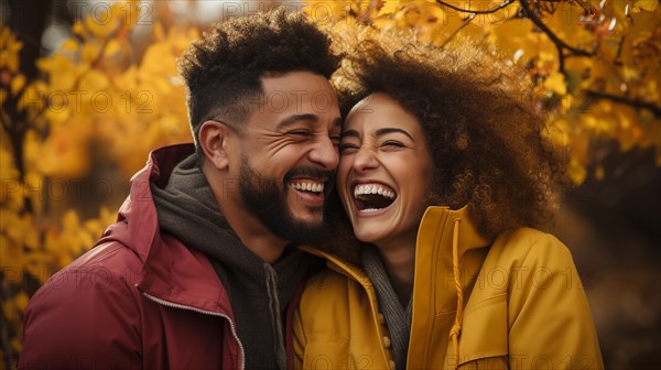 Happy warmly dressed young loving multi-ethnic couple laughing as they enjoy the beautiful fall leaves in the park