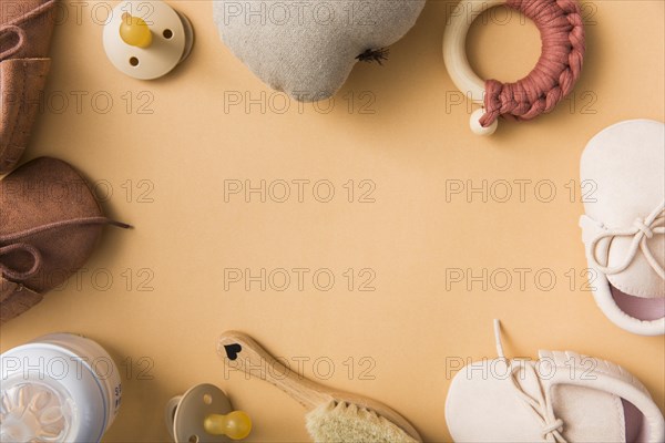 Blank space text with pair shoes pacifier stuffed pear brush milk bottle orange backdrop