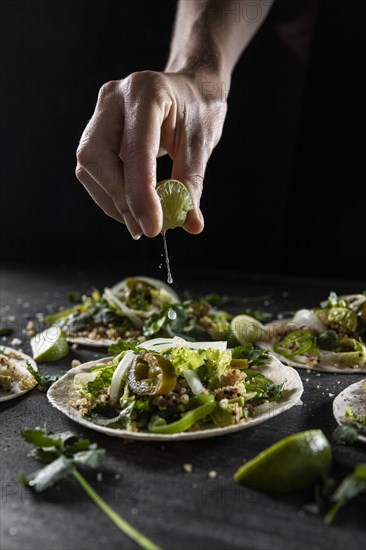 Close up hand squeezing lime taco