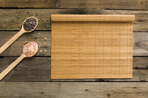 Pink black salt wooden spoons with mat wooden background