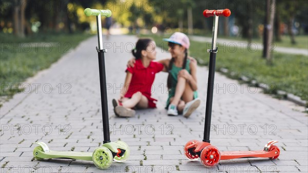 Push scooters front girls sitting walkway park